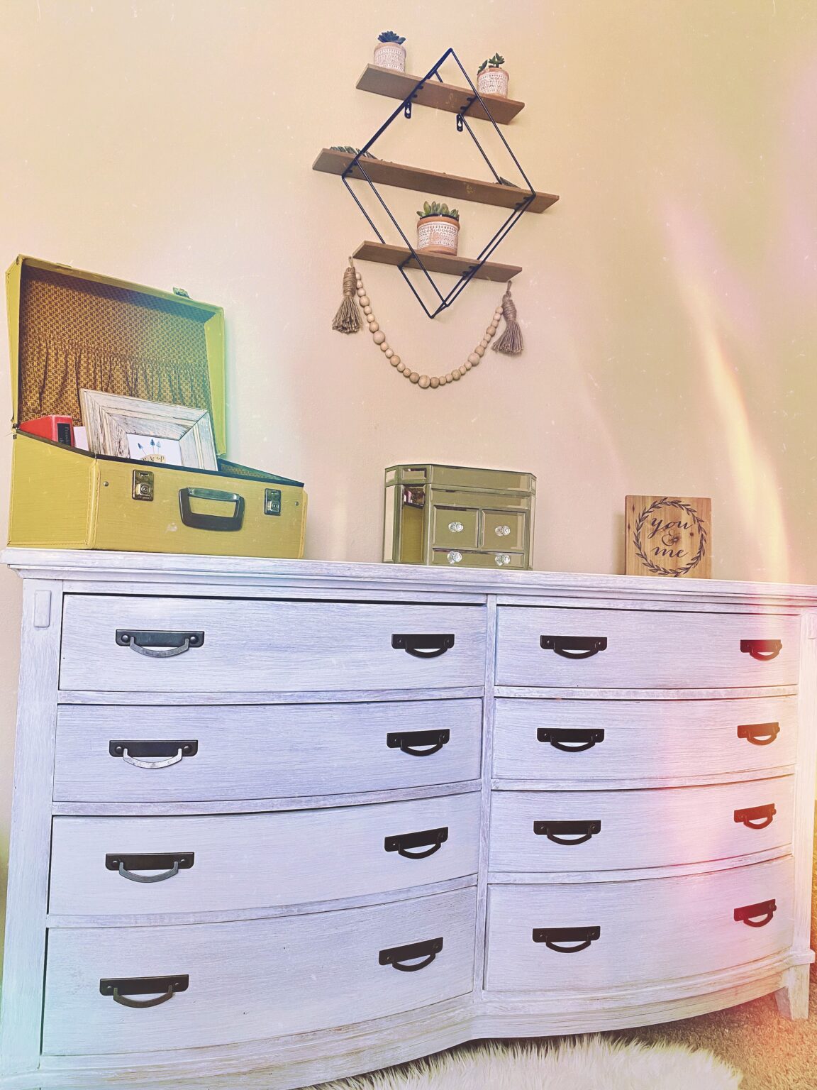 Painted dresser with white drawers and a gold-toned top, displayed beneath a decorative anchor.