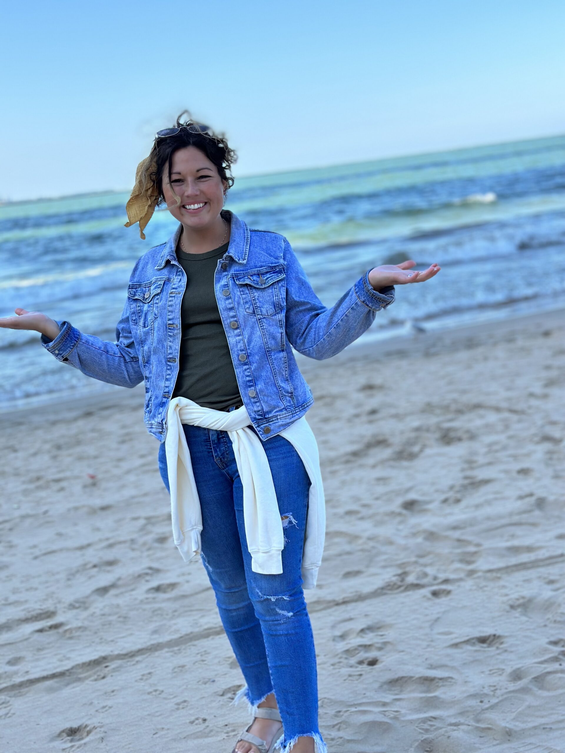 Kimmie Liette smiling on the beach with her hands outstretched